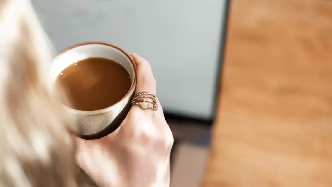 Woman drinking a hot cup of coffee at a café with a pastry to turn a bad day around