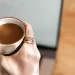 Woman drinking a hot cup of coffee at a café with a pastry to turn a bad day around