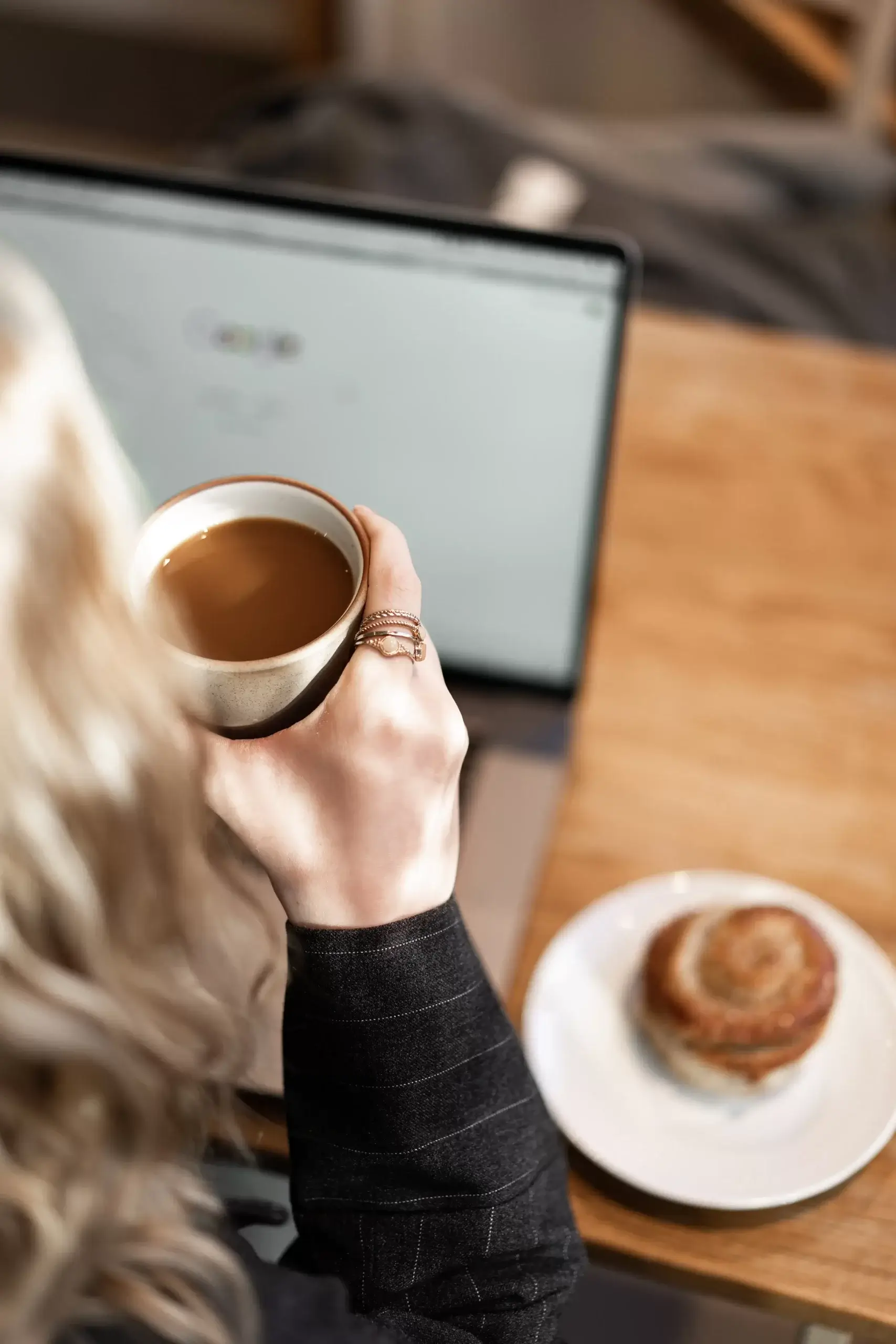 Woman drinking a hot cup of coffee at a café with a pastry to turn a bad day around